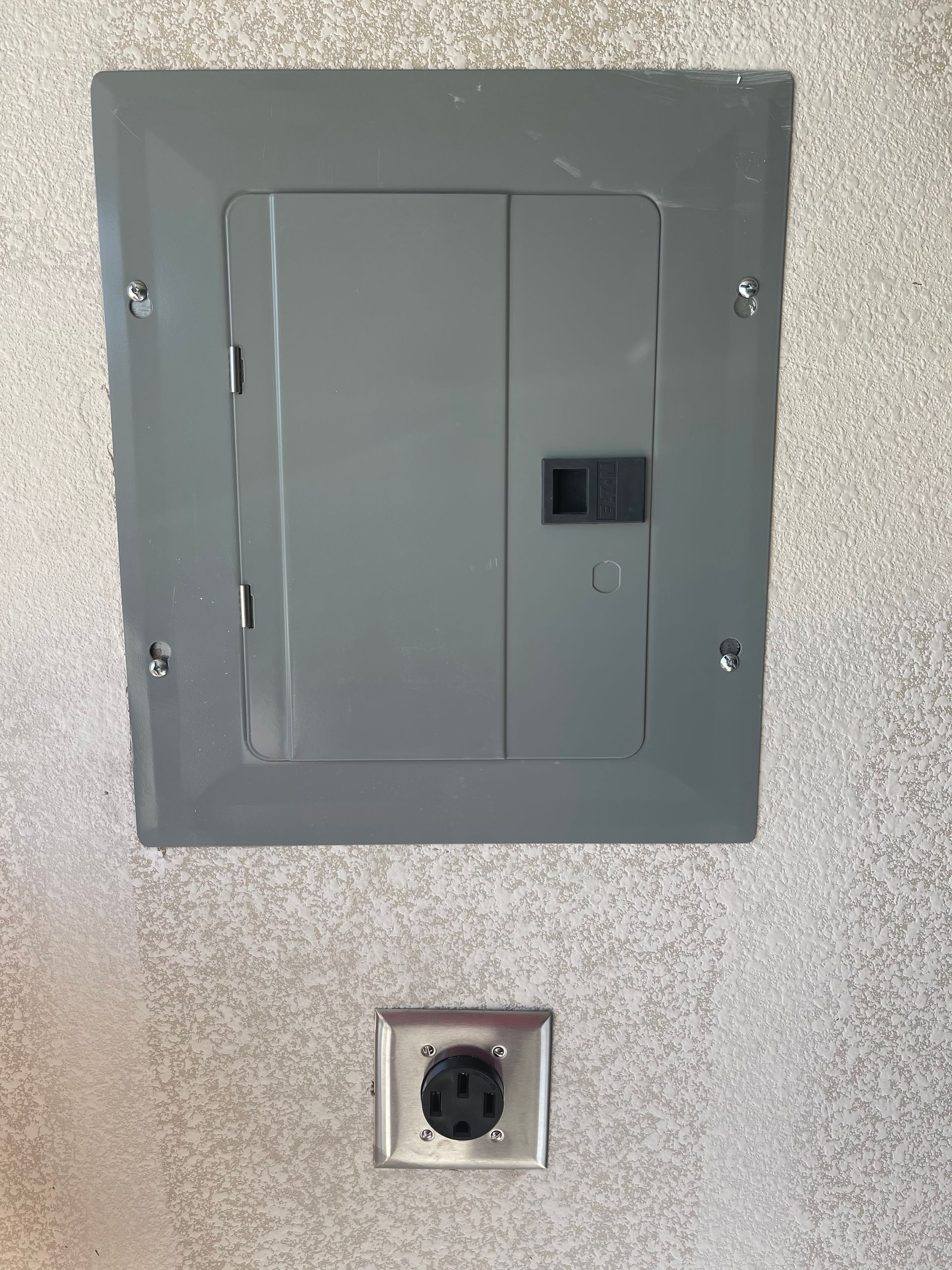 There is a electrical box on the wall next to a socket.