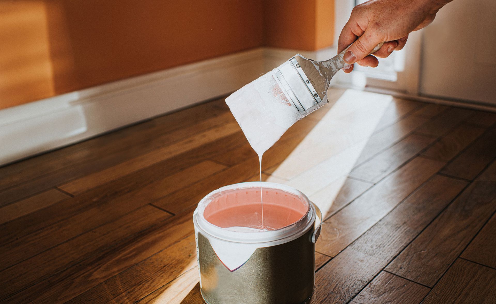 Paintbrush dipped in white paint during interior painting services for a living room.