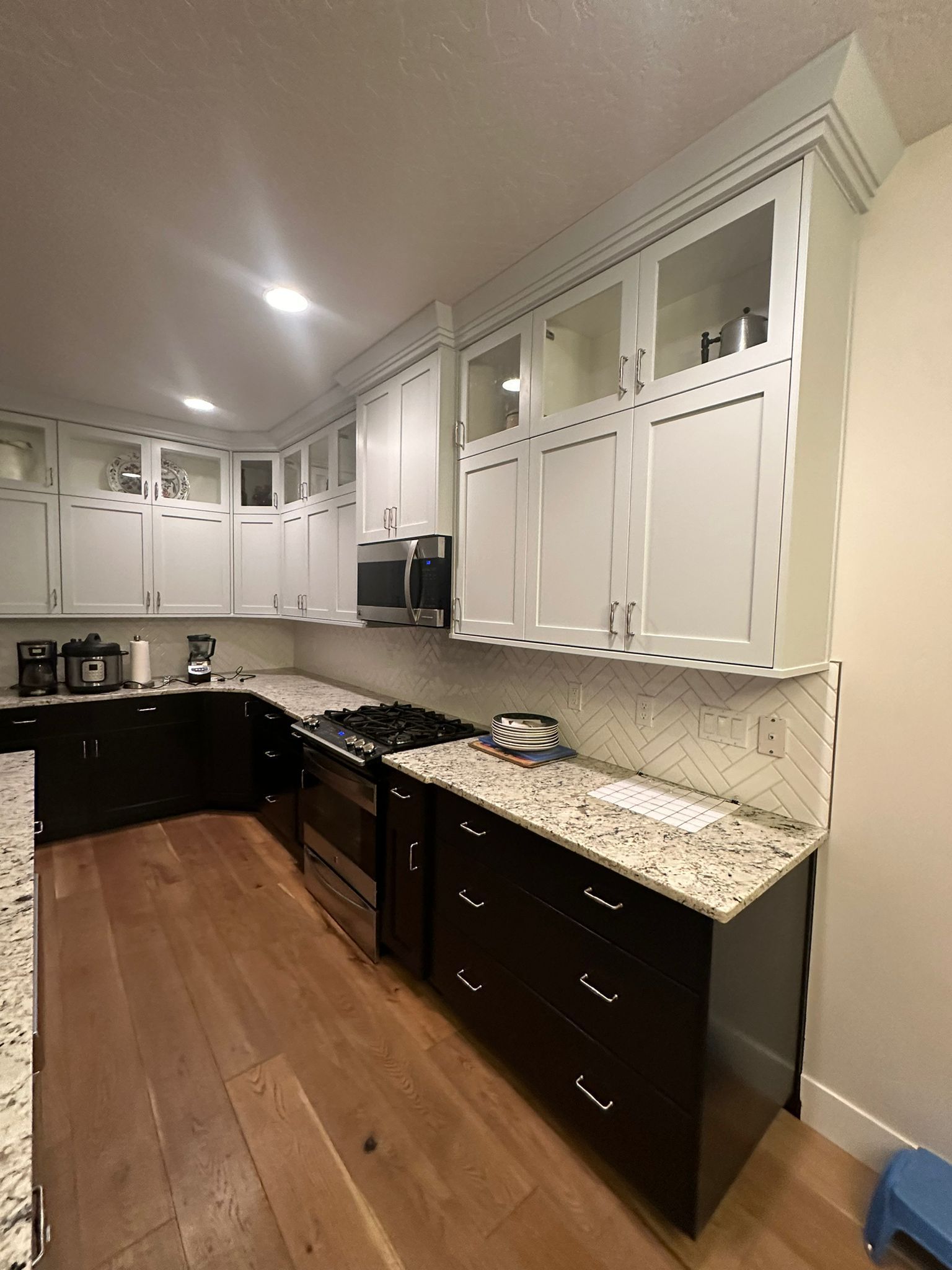 A kitchen with black cabinets and white cabinets and granite counter tops.