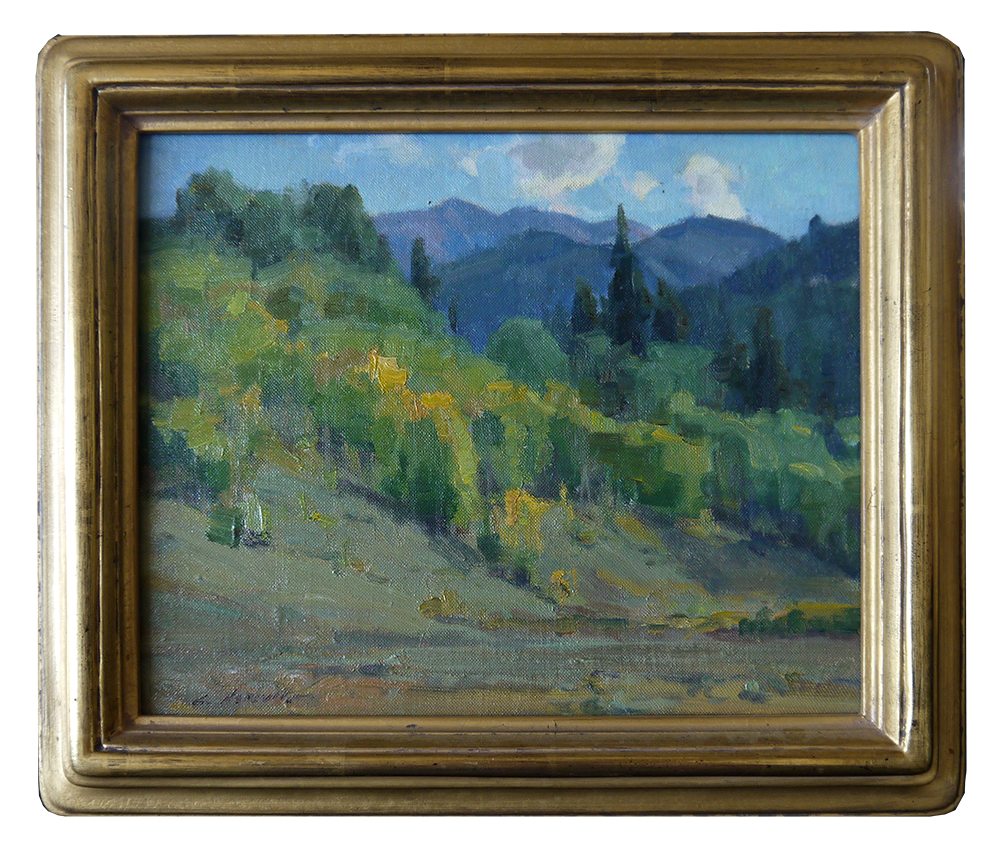 A framed painting of a landscape with mountains in the background