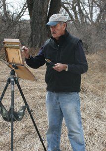 A man is painting on a tripod in a field