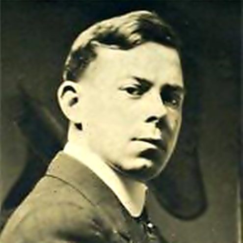 A young man in a suit and tie is looking at the camera in a black and white photo.