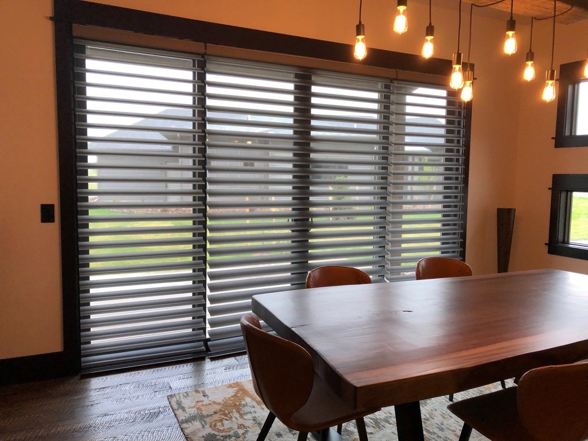 A dining room with a wooden table and chairs and sliding glass doors.