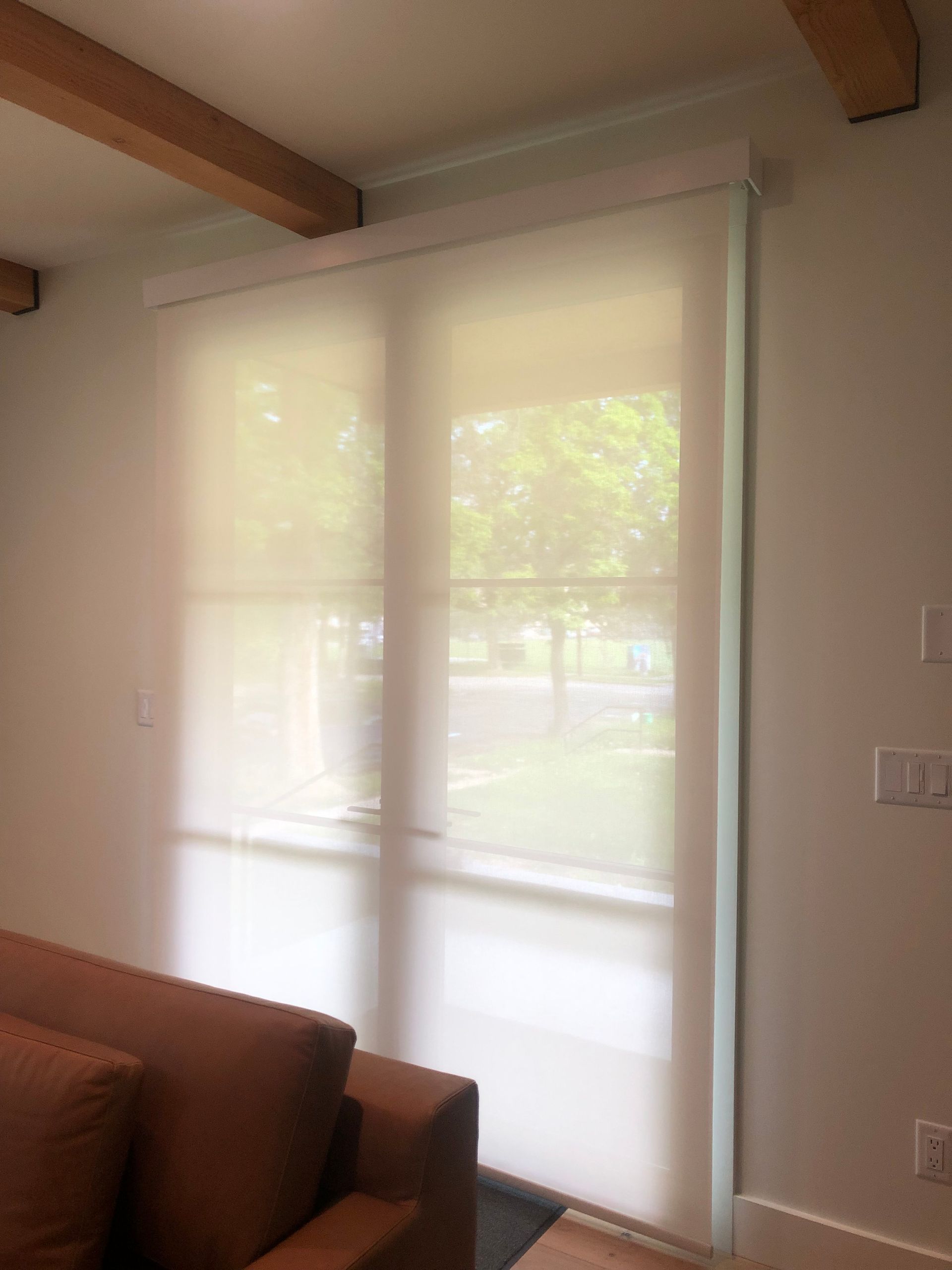 A living room with a brown couch and white blinds on the windows.