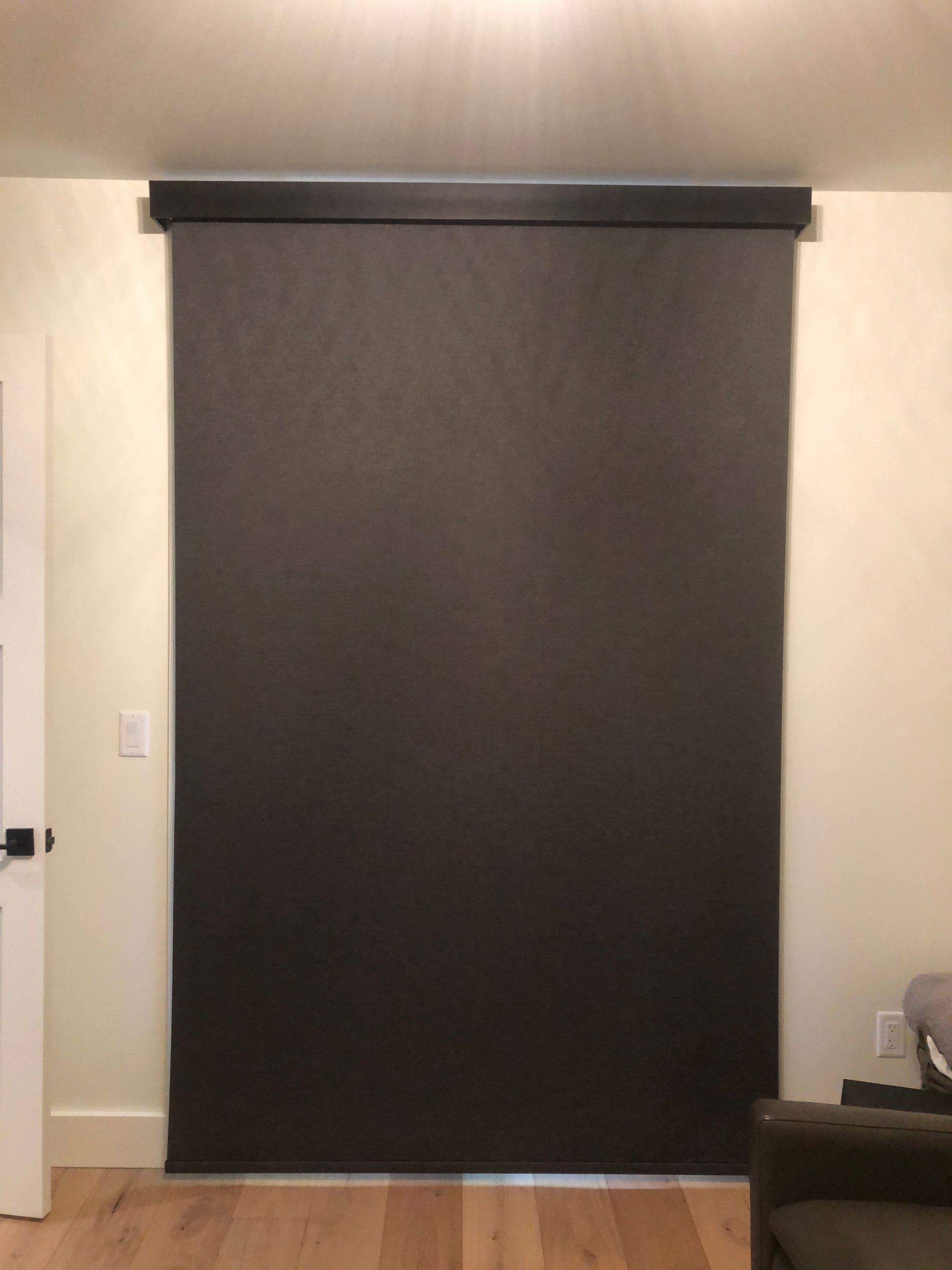 A large black blind is hanging on a wall in a living room.