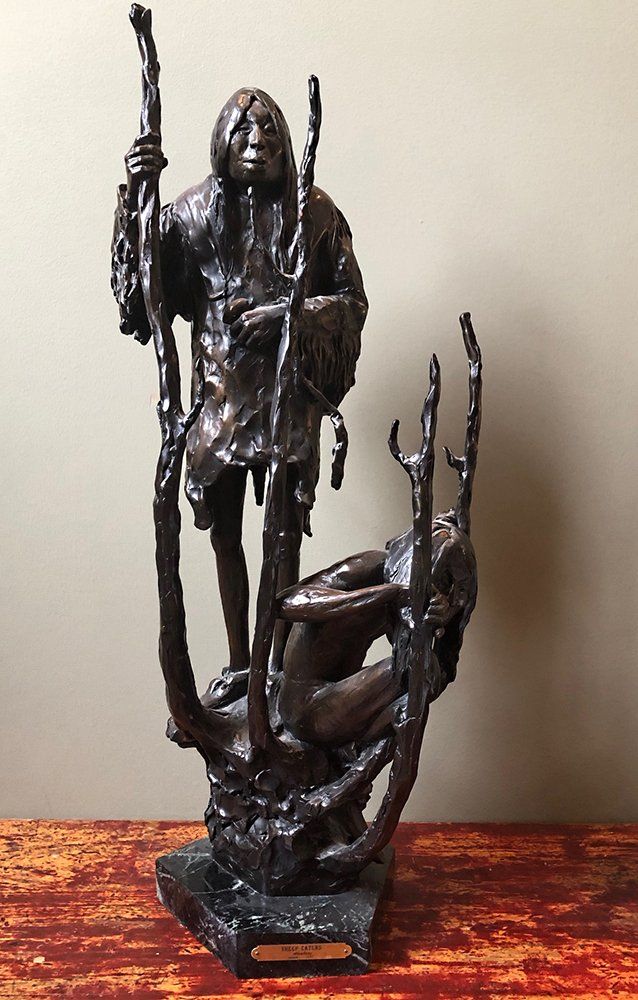 A bronze statue of a man holding a stick standing next to a woman