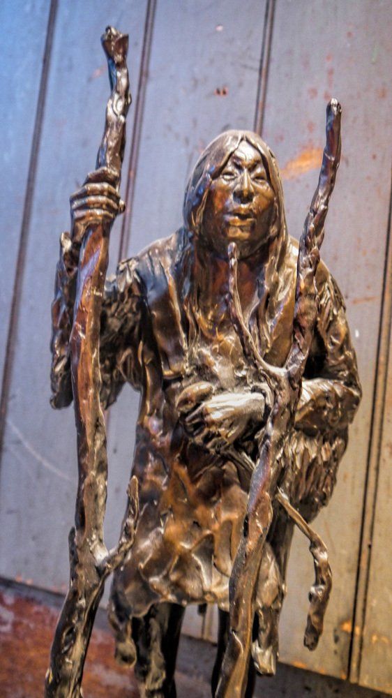 A bronze statue of a man holding two sticks.