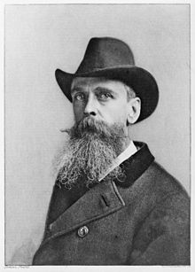 A black and white photo of a man with a beard wearing a hat and coat.