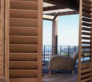 A wicker chair is sitting on a wooden deck under a pergola.