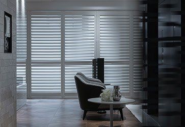 A living room with a couch , table and shutters on the windows.