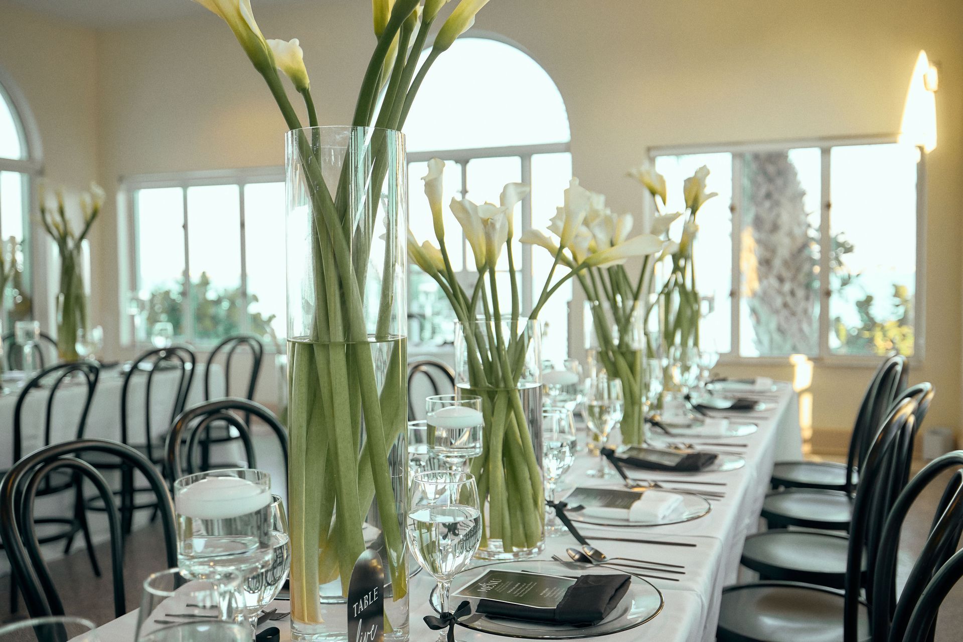 A long table set for a wedding reception with vases of flowers on it.