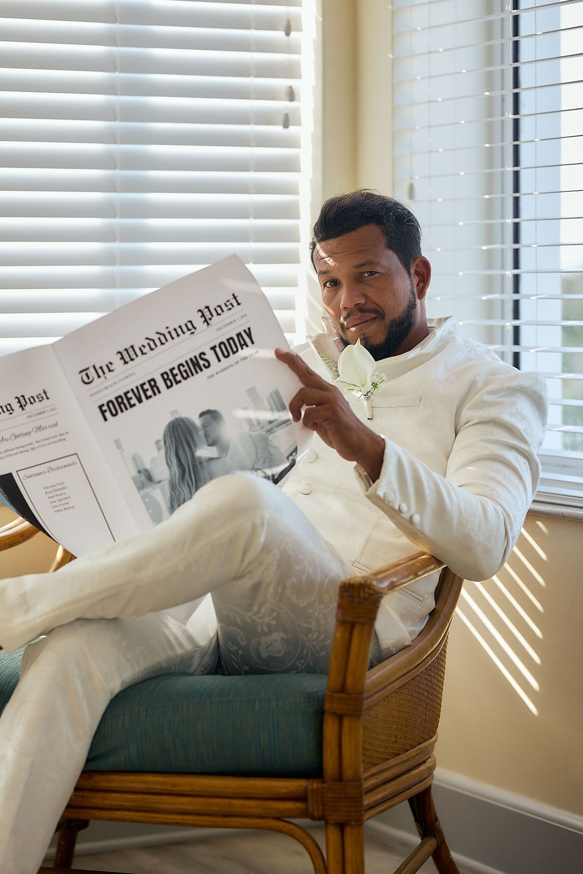 A man is sitting in a chair reading a newspaper.