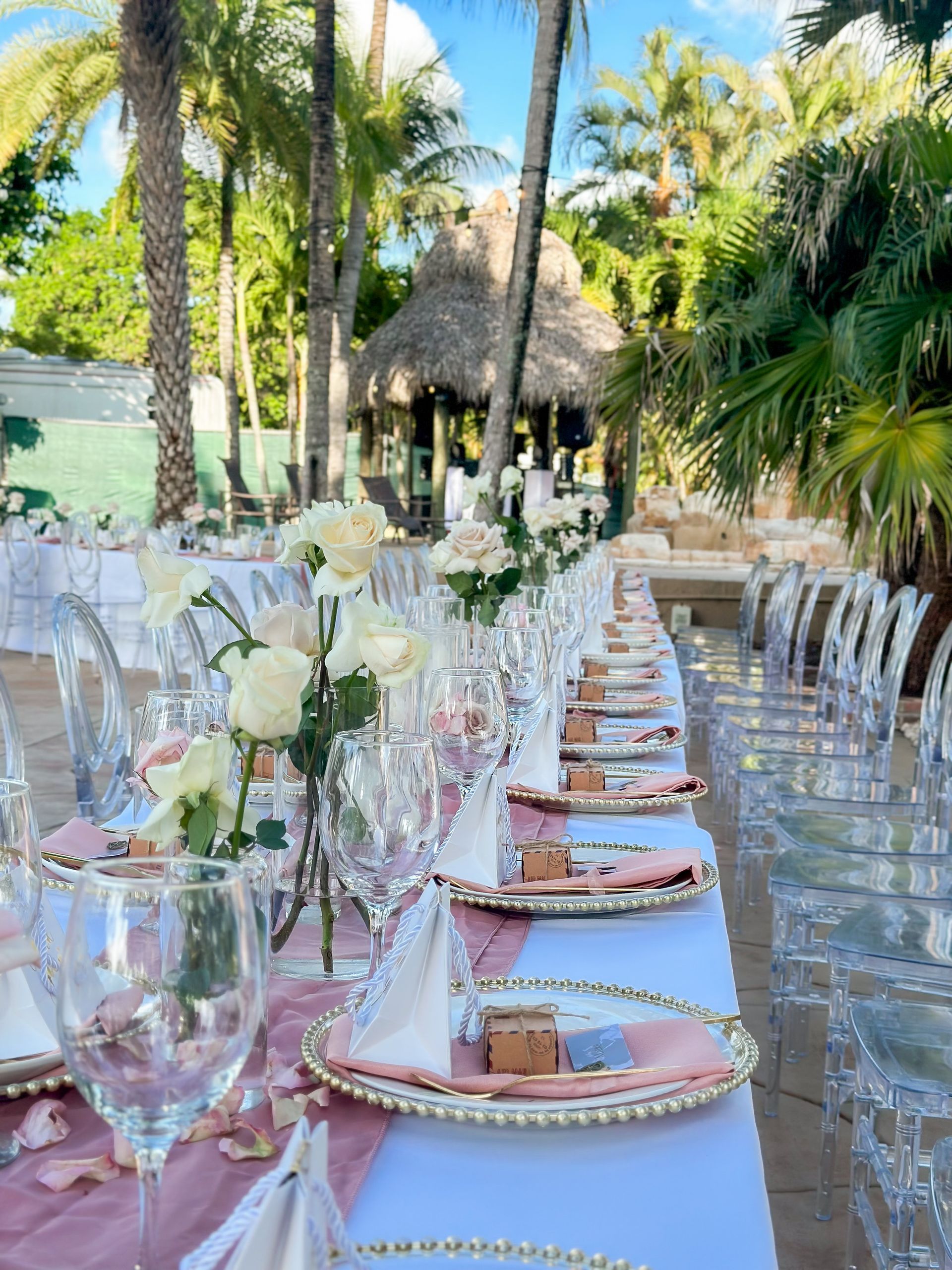 A long table with plates , glasses , napkins and flowers on it.