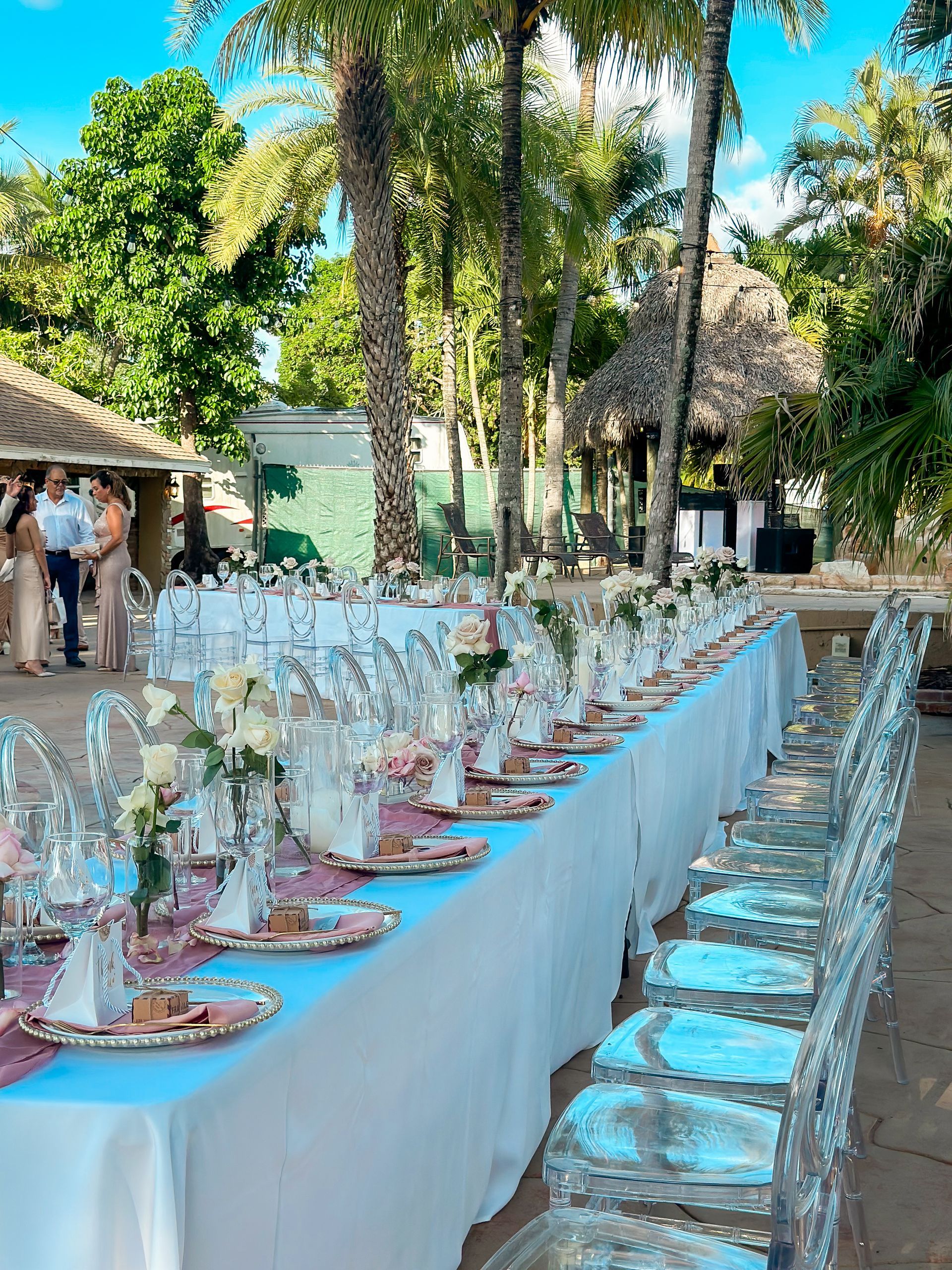 A long table with plates , glasses , and flowers on it is set up for a wedding reception.
