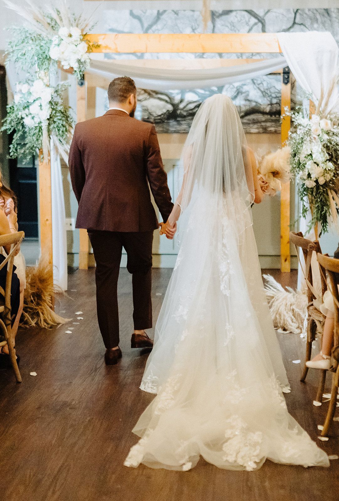 A bride and groom are walking down the aisle at their wedding holding hands.