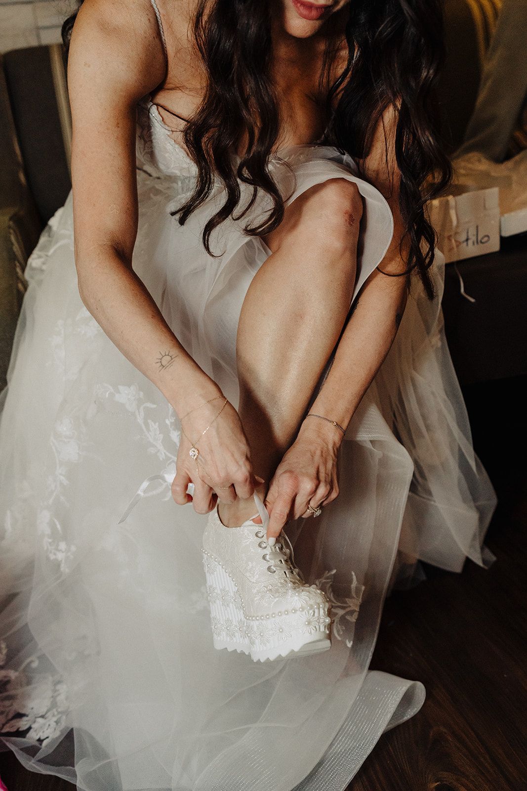 A woman in a wedding dress is tying her shoes.