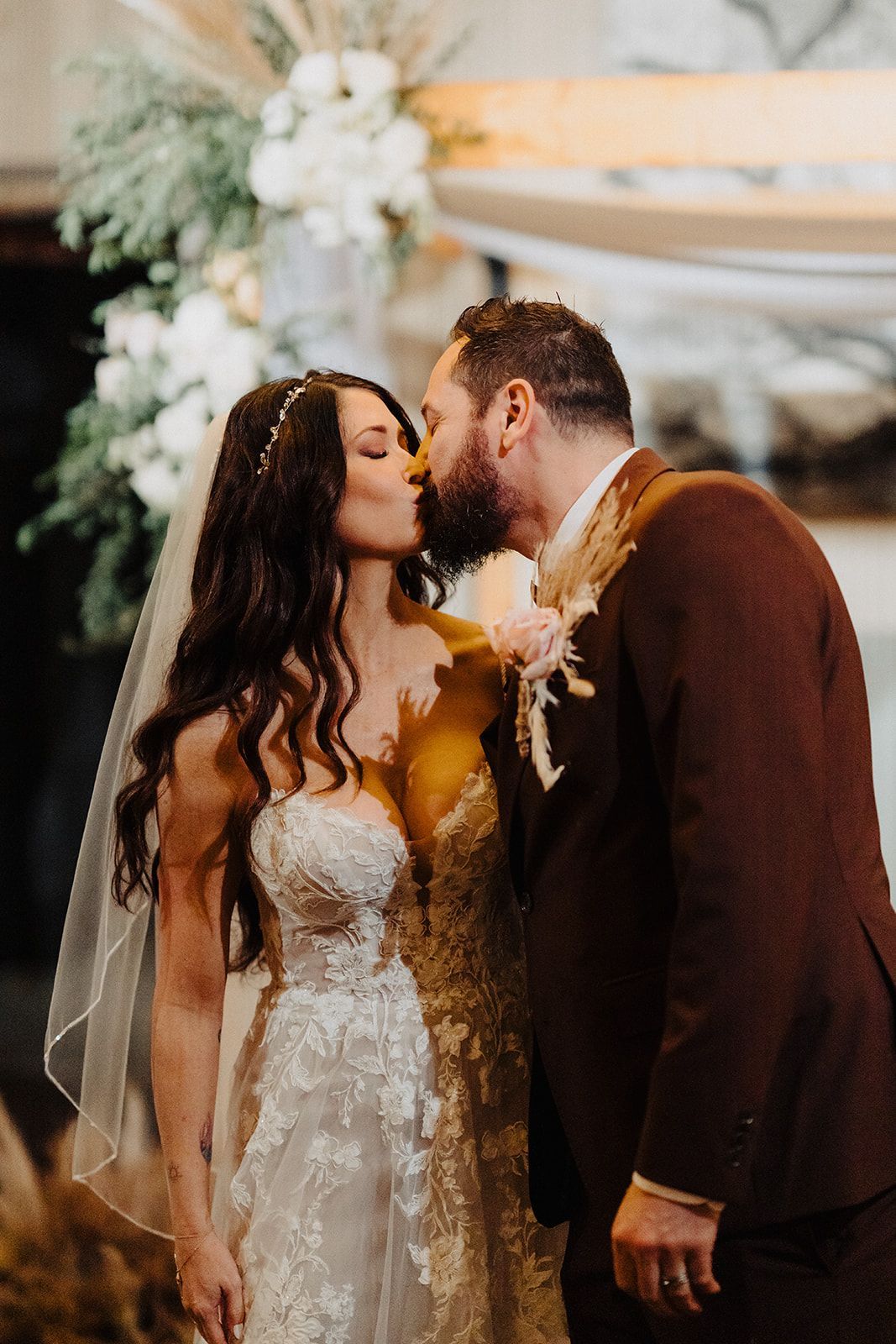 A bride and groom are kissing at their wedding ceremony.