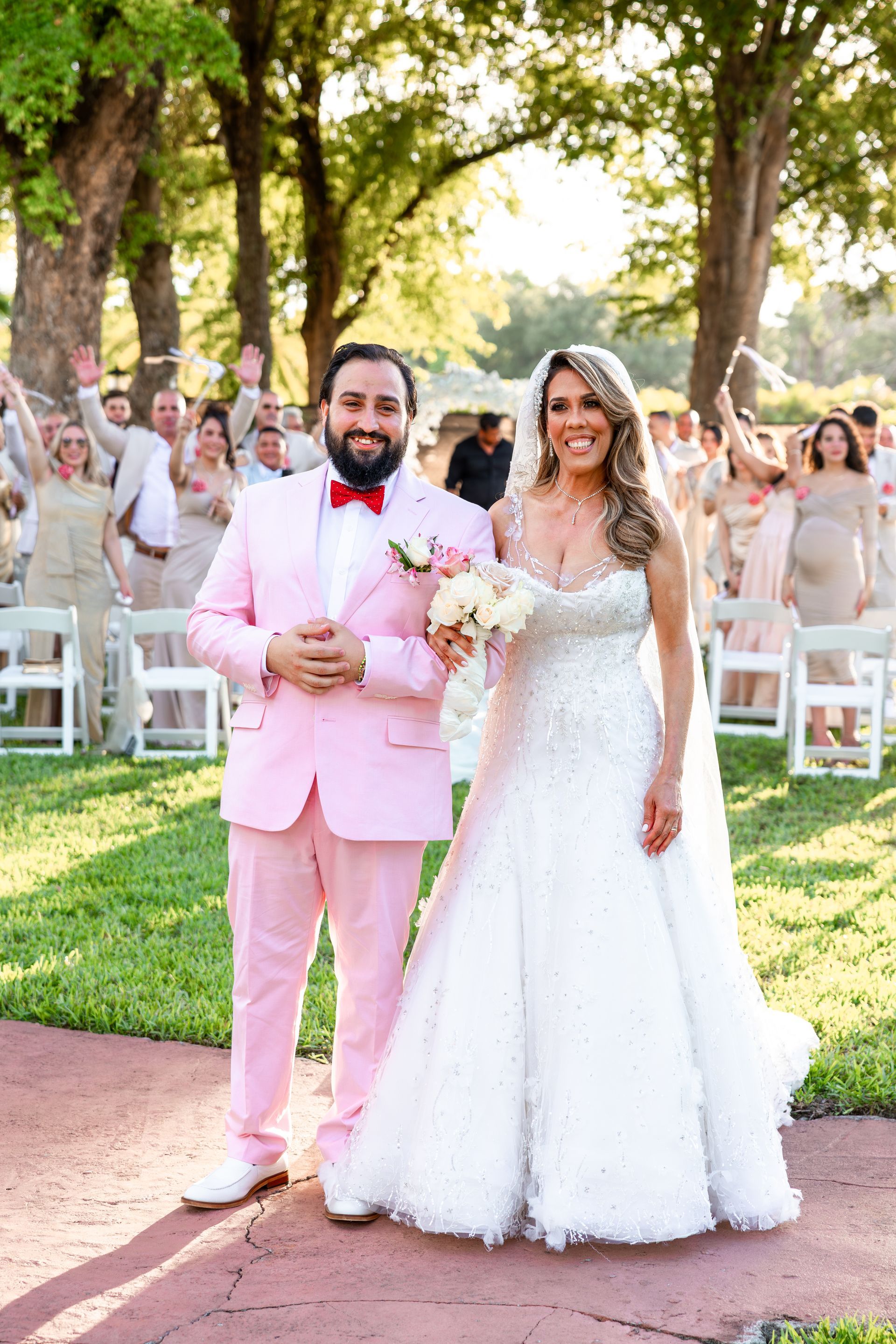 A bride and groom are standing next to each other in front of their wedding party.