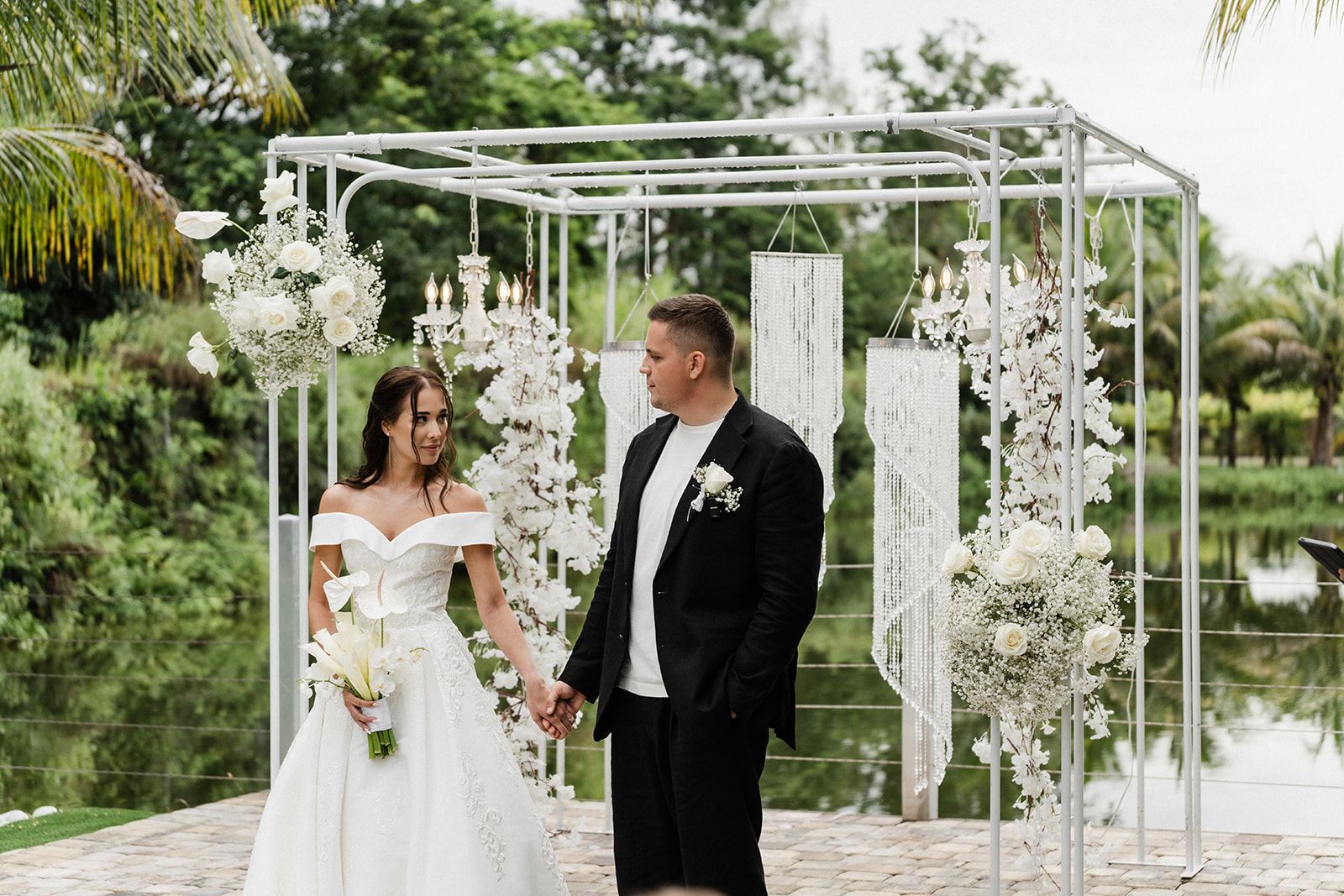 A table with a white tablecloth and candles under a wooden arch.