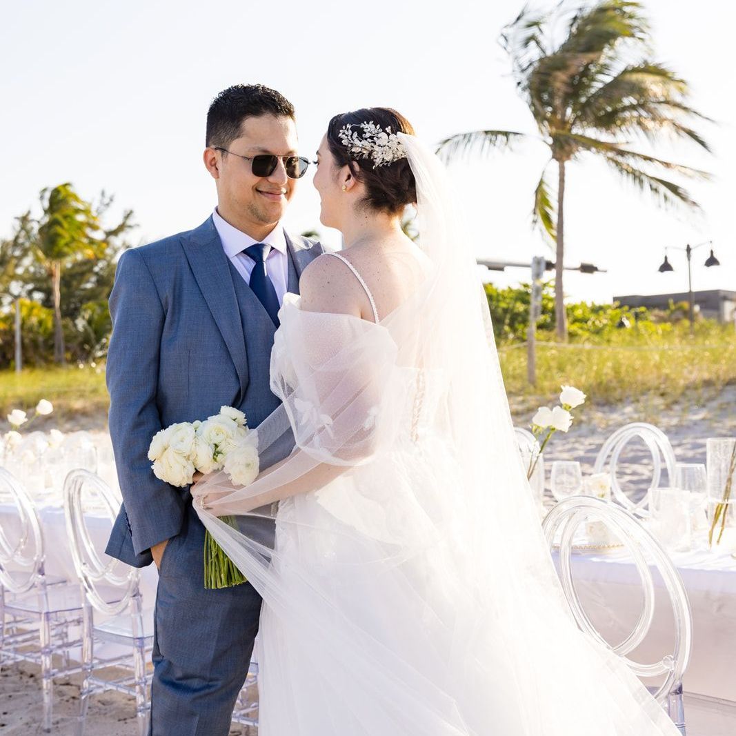 A bride and groom are posing for a picture on the beach