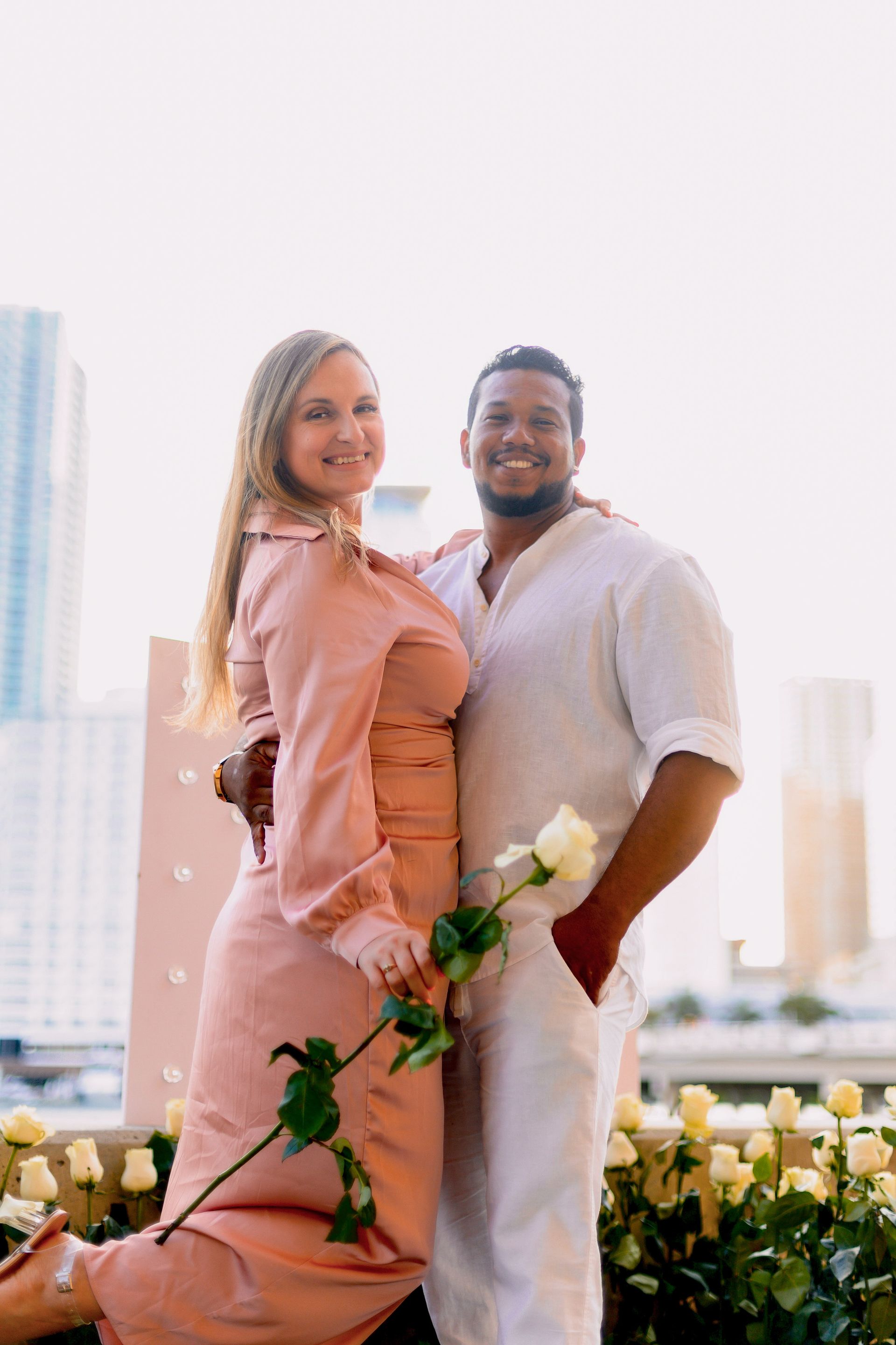 A man and a woman are standing next to each other holding roses.