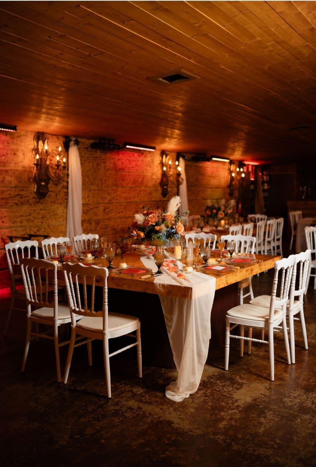 A long wooden table with white chairs in a room.
