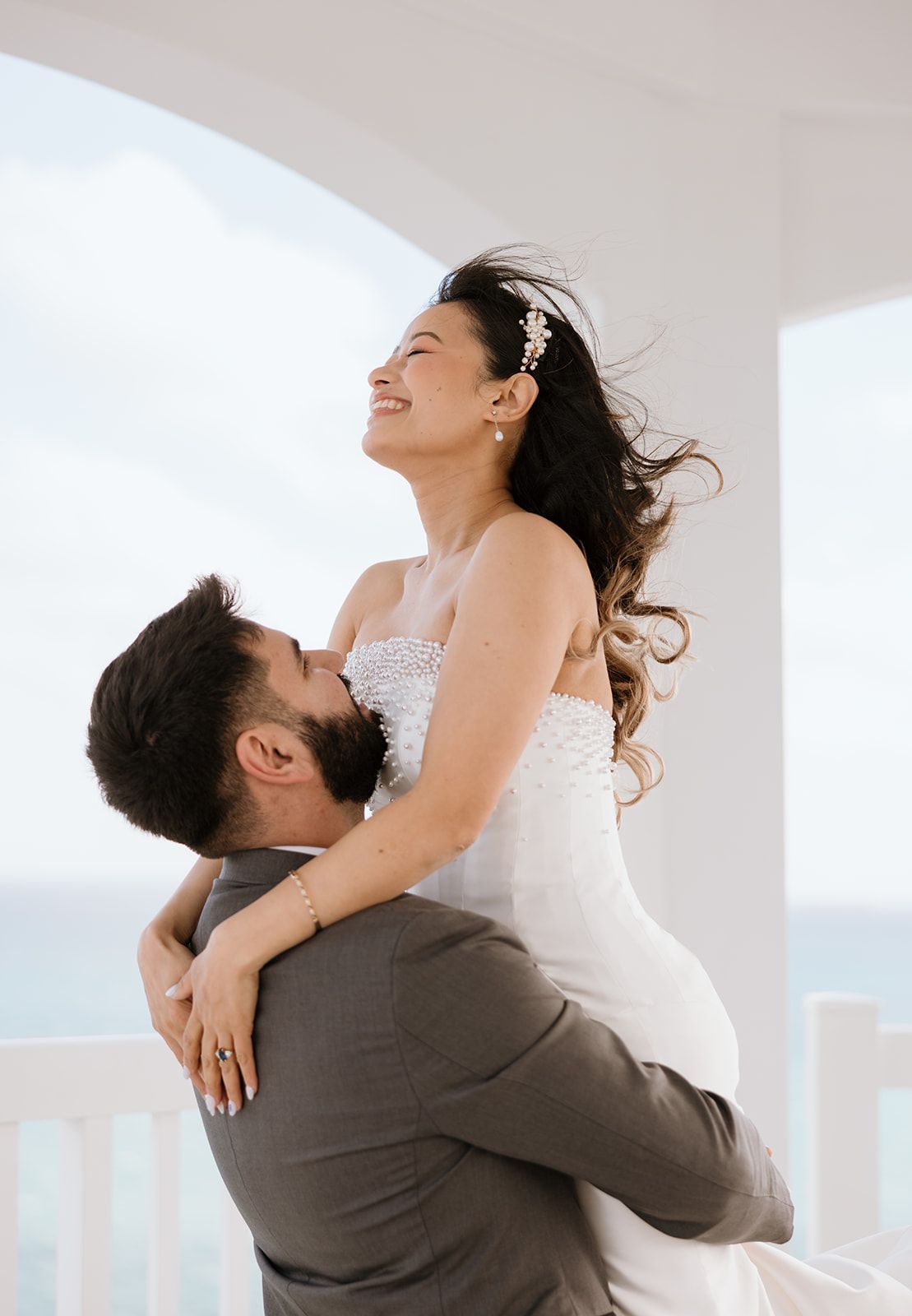 A man is holding a bride in his arms and kissing her.