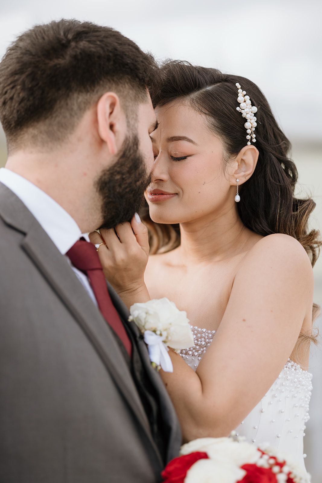 A bride and groom are kissing each other on the forehead.