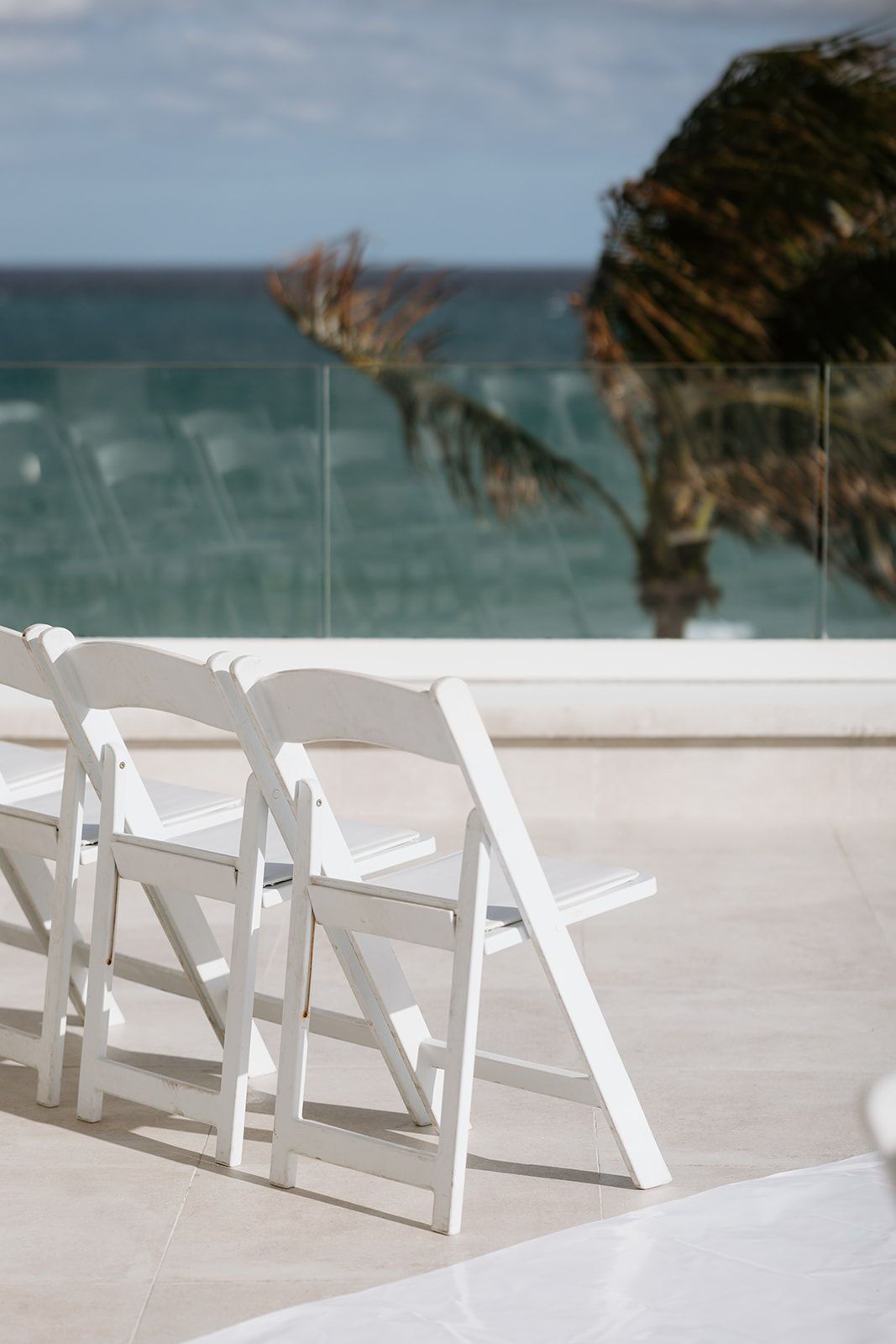 A row of white folding chairs with a view of the ocean.