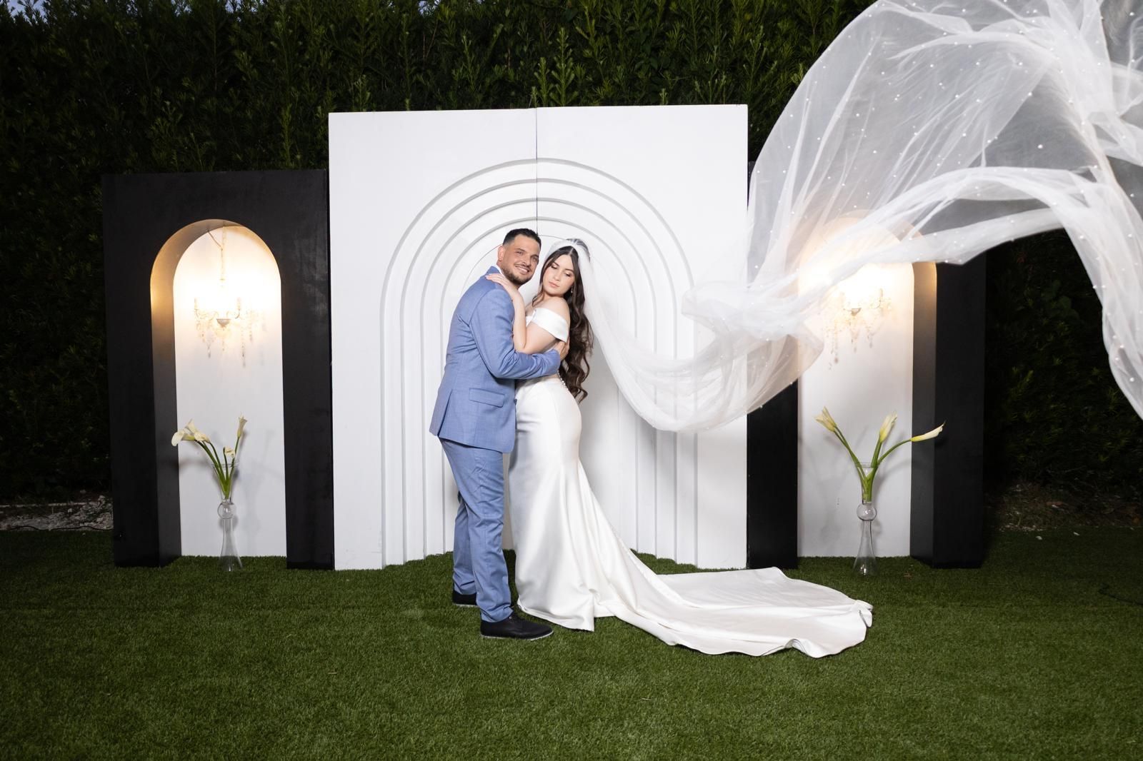A long table with plates , glasses , napkins and flowers on it.