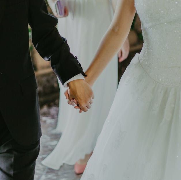 A bride and groom are holding hands during their wedding ceremony.