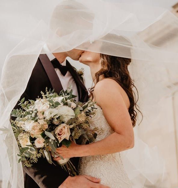 A bride and groom kissing under a veil