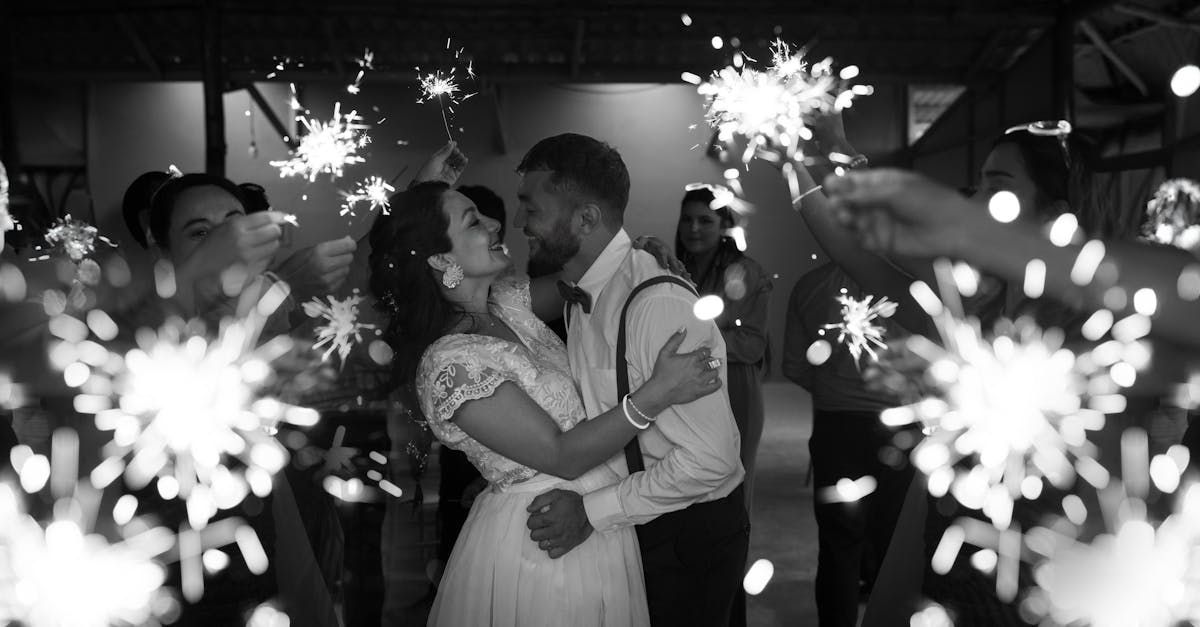 A bride and groom are kissing while holding sparklers at their wedding reception.