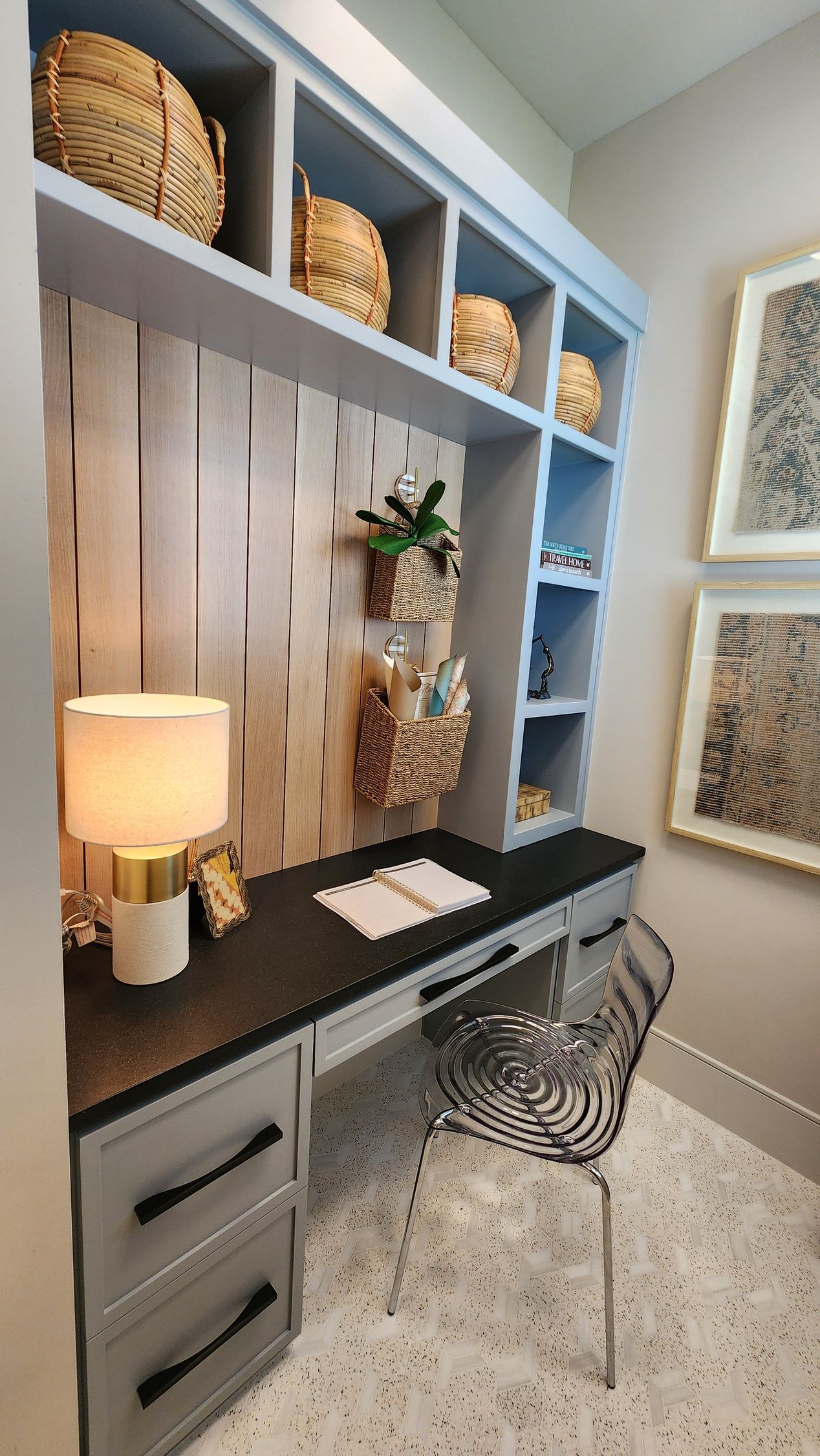 A home office with a desk , chair , lamp and shelves.