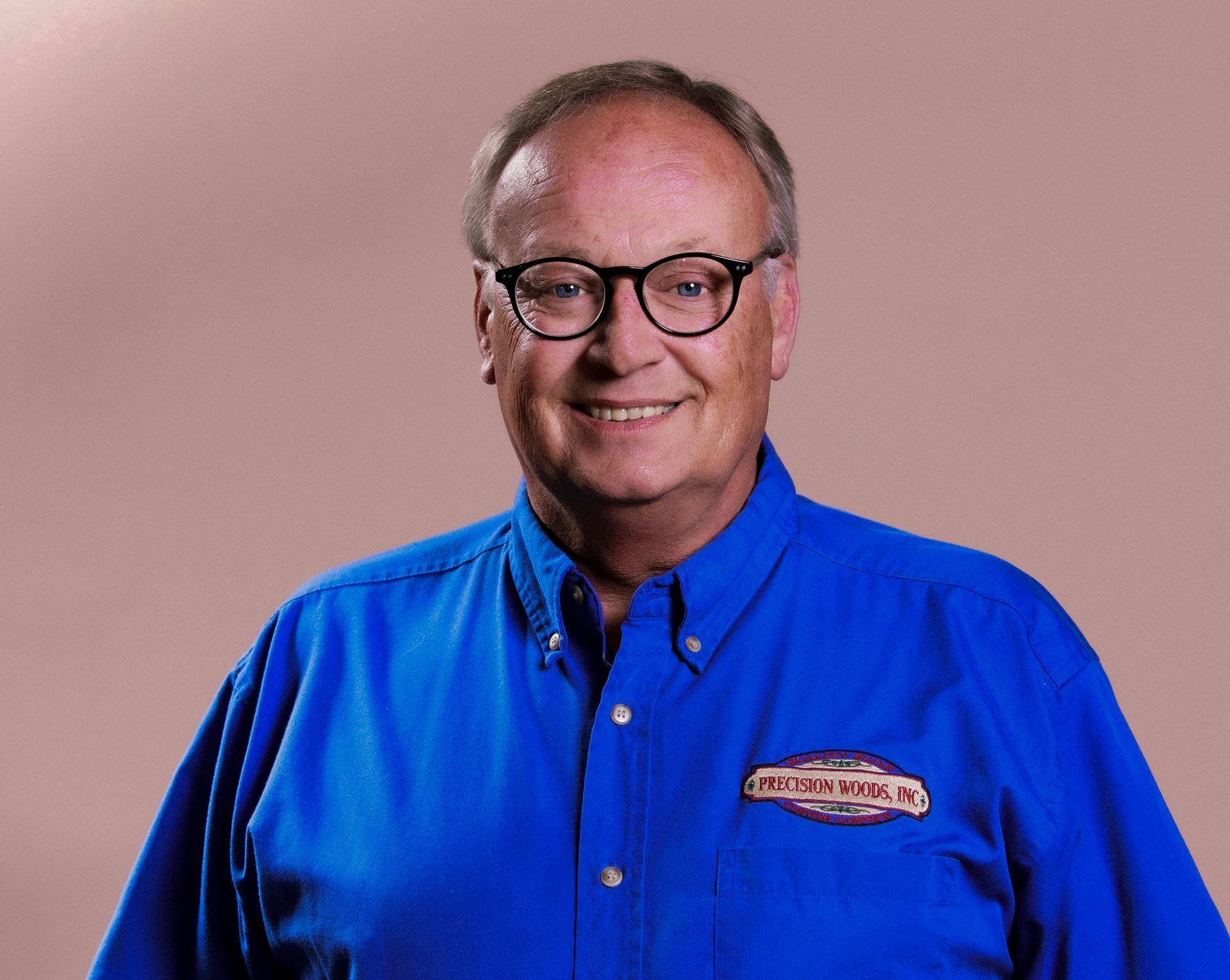 A man wearing glasses and a blue shirt is smiling for the camera.