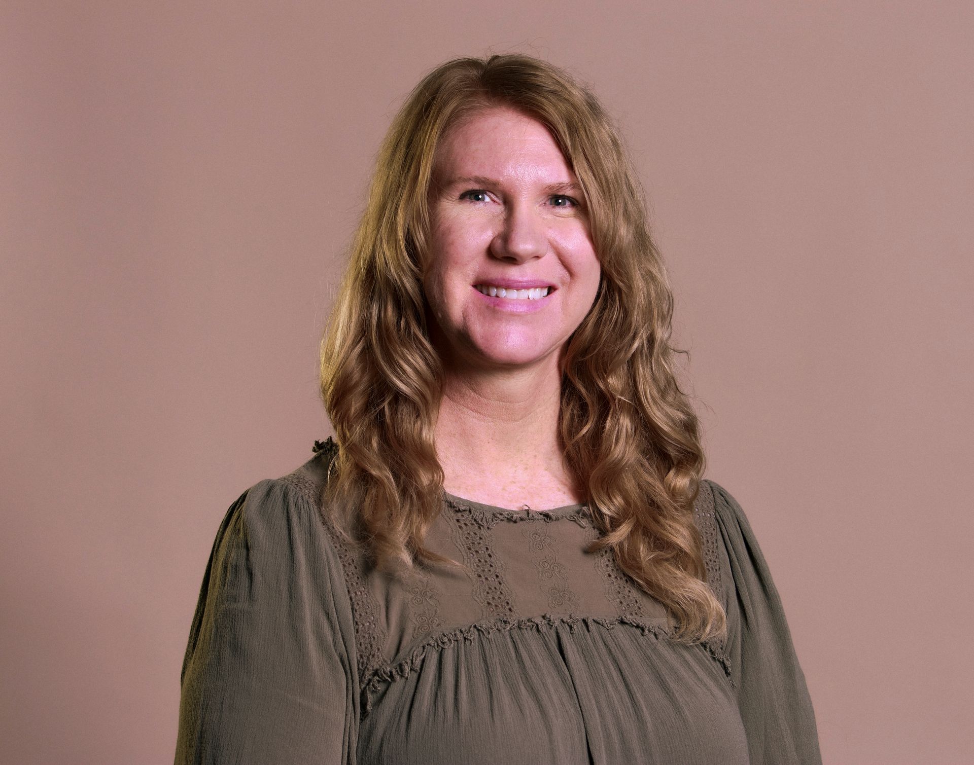 A woman in a green dress is smiling for the camera.