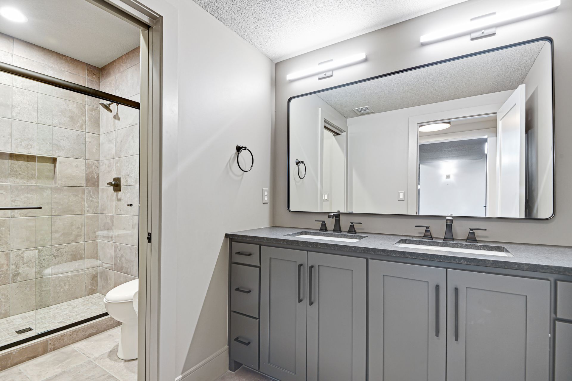 A bathroom with two sinks , a toilet , and a large mirror.