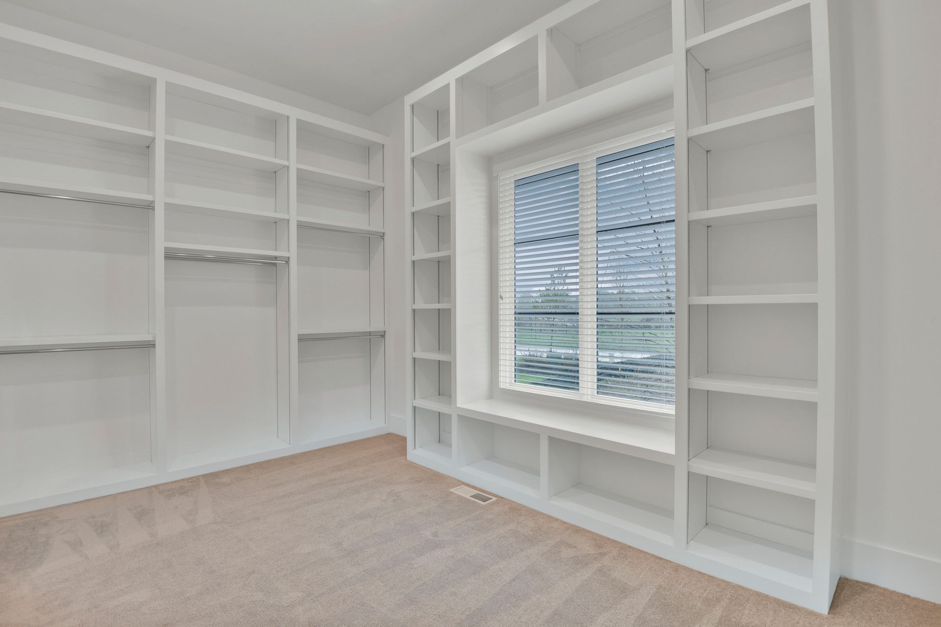 An empty walk in closet with lots of shelves and a window.
