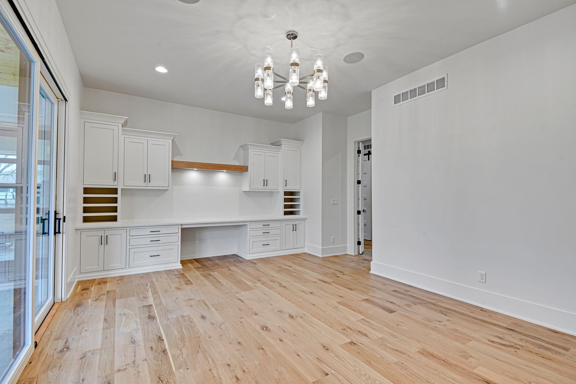 An empty living room with hardwood floors and white cabinets.