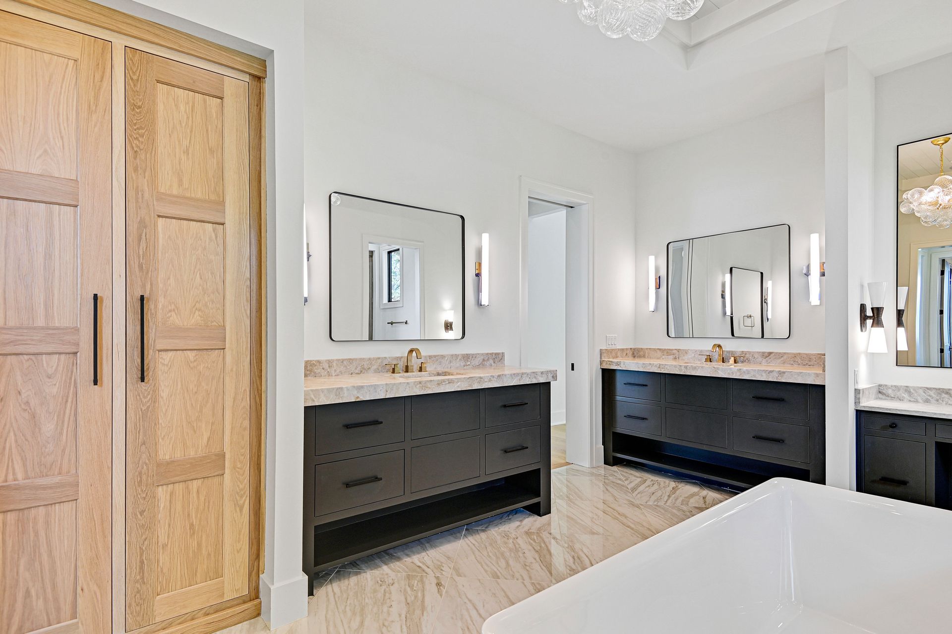 A bathroom with two sinks , two mirrors and a bathtub.