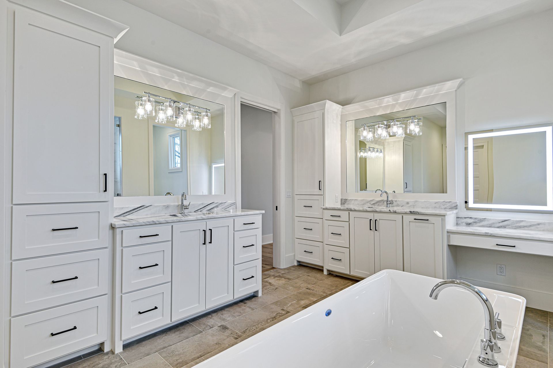 A bathroom with a bathtub , sinks , mirrors and cabinets.