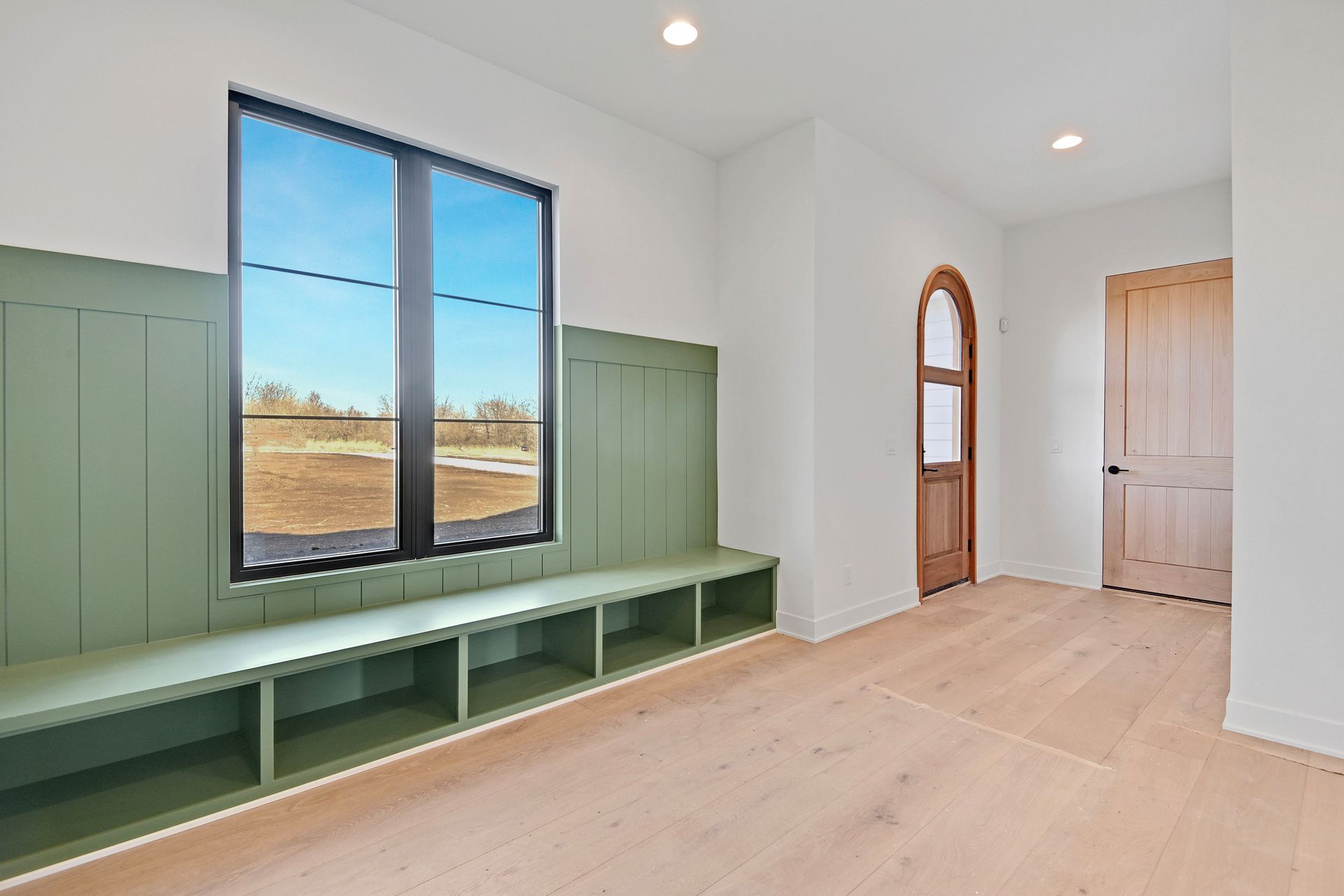 An empty room with a bench and two windows.