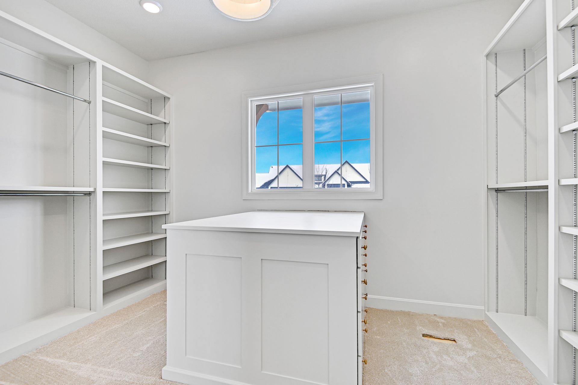 A walk in closet with lots of shelves and a window.
