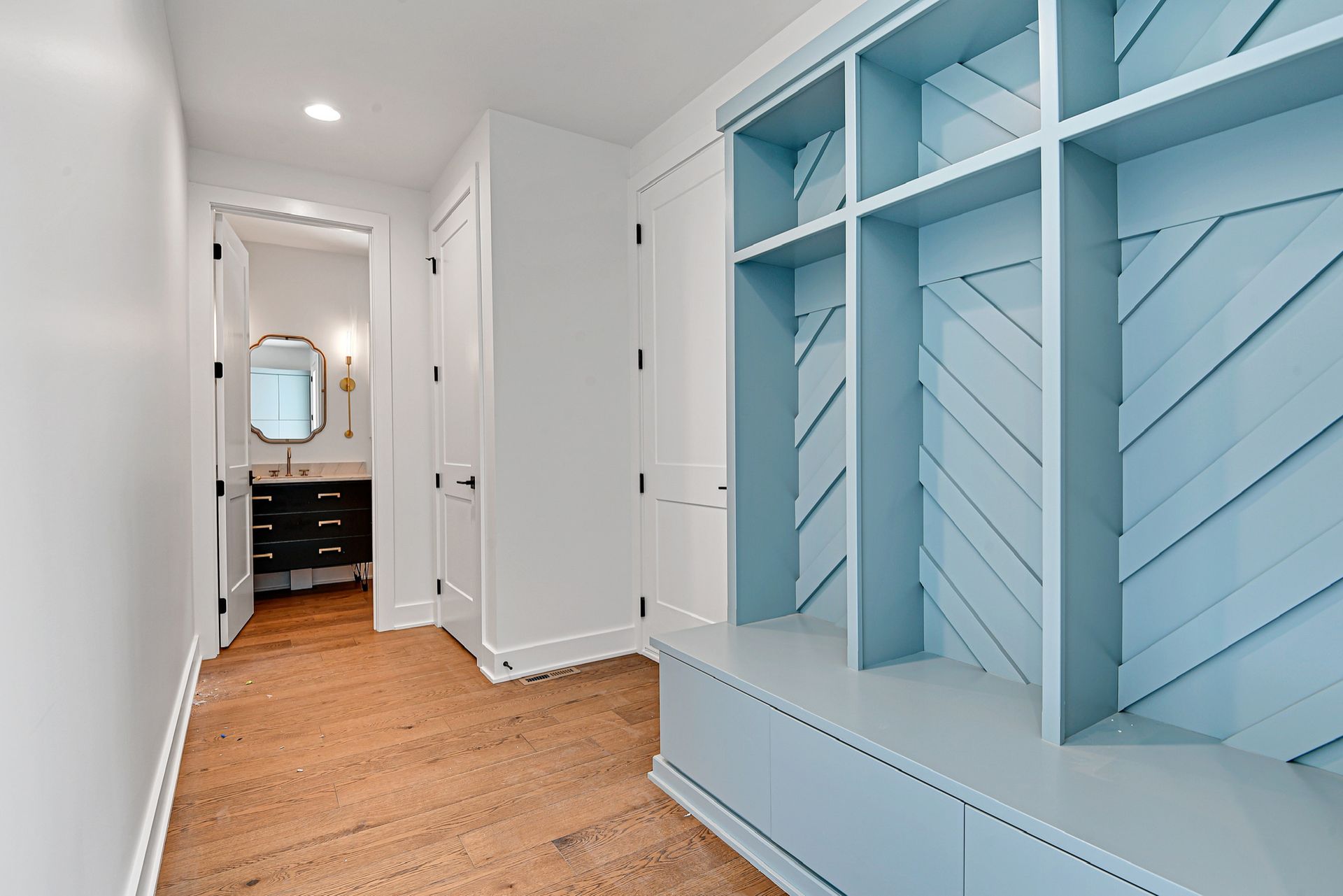 A hallway with blue shelves and a bathroom in the background.
