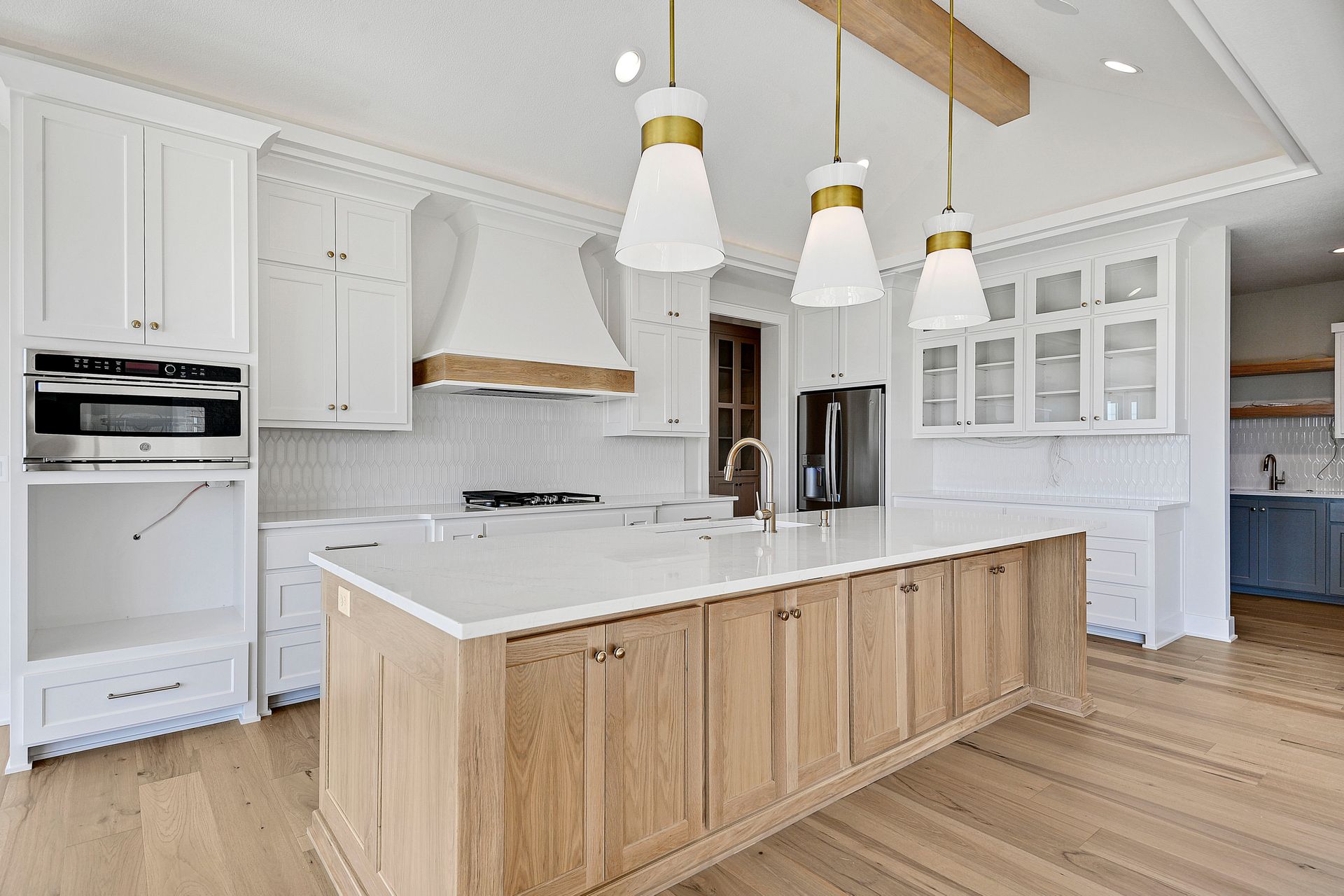 A kitchen with white cabinets and wooden cabinets and a large island.
