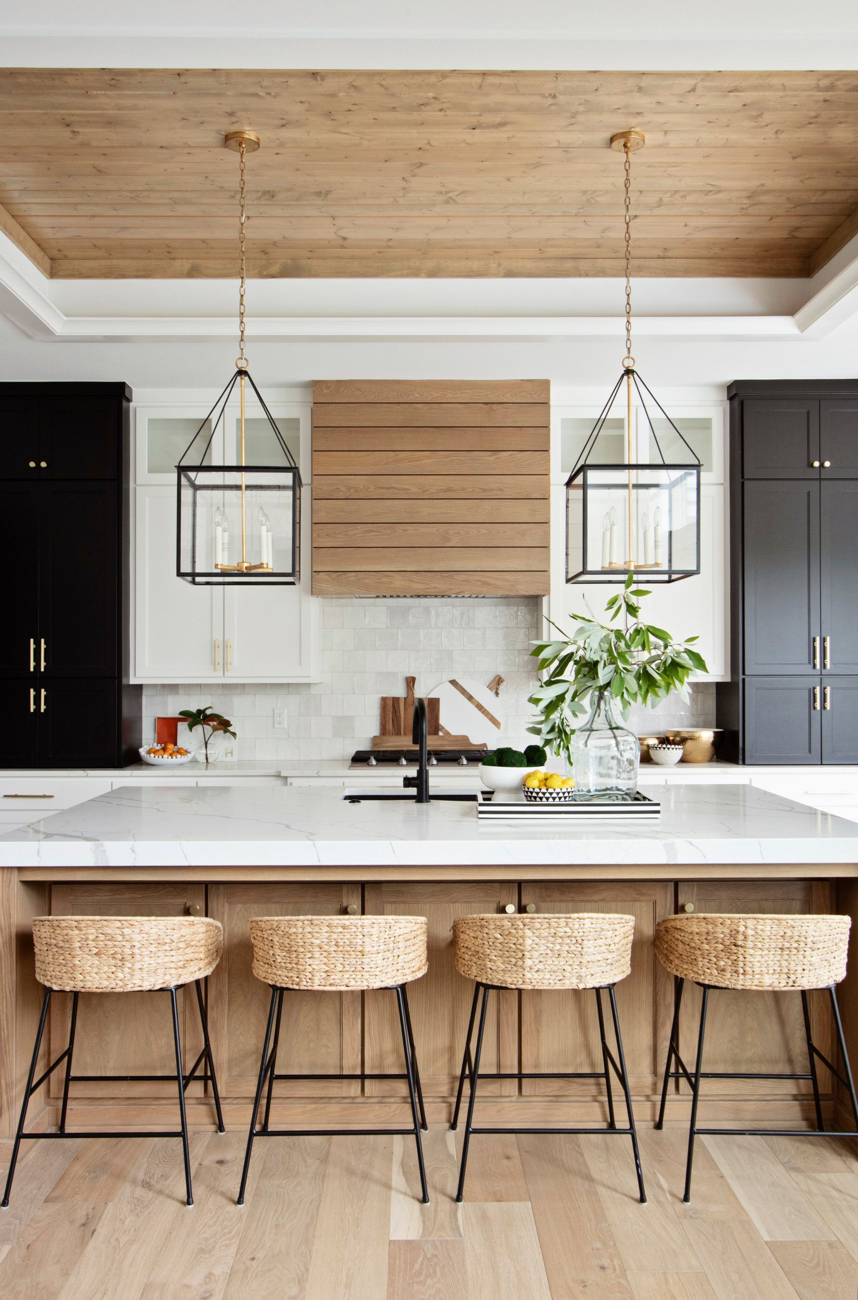 A kitchen with a large island and wicker stools.