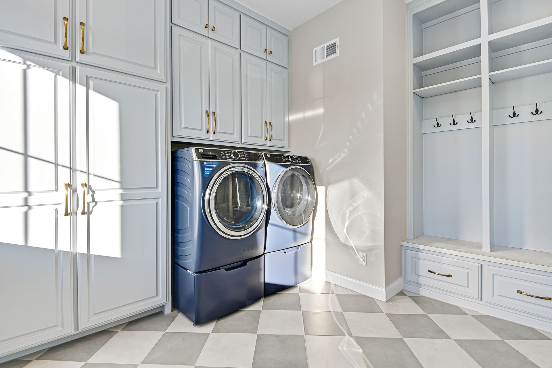 A laundry room with a washer and dryer and a checkered floor.