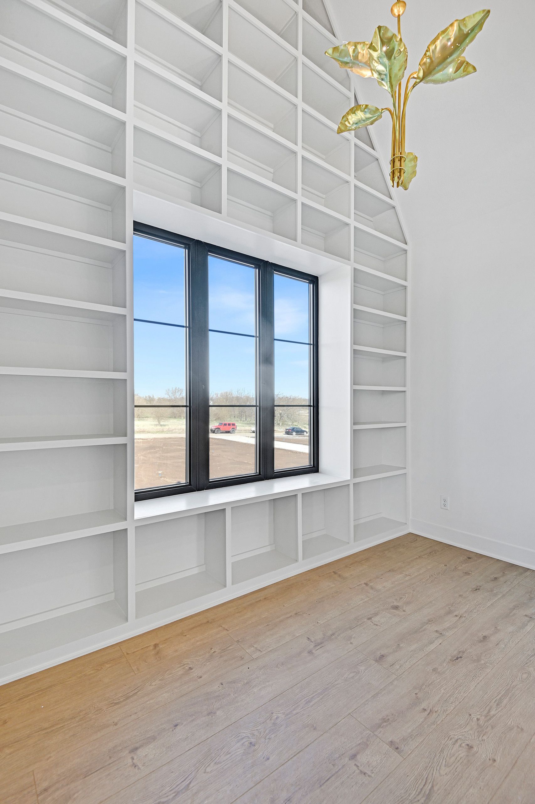 An empty room with a large window and lots of shelves.