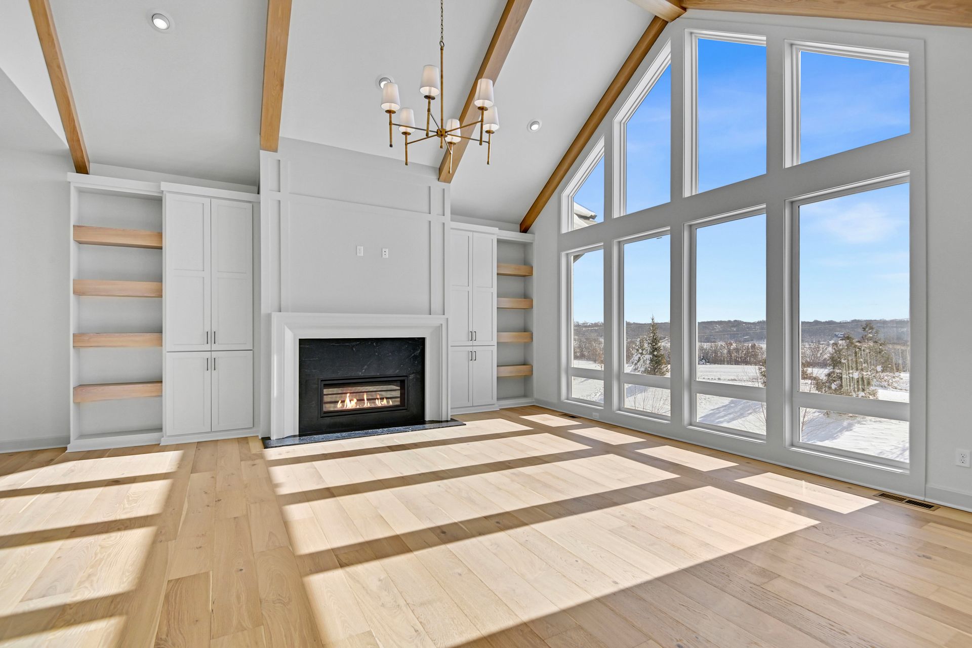 An empty living room with a fireplace and lots of windows.