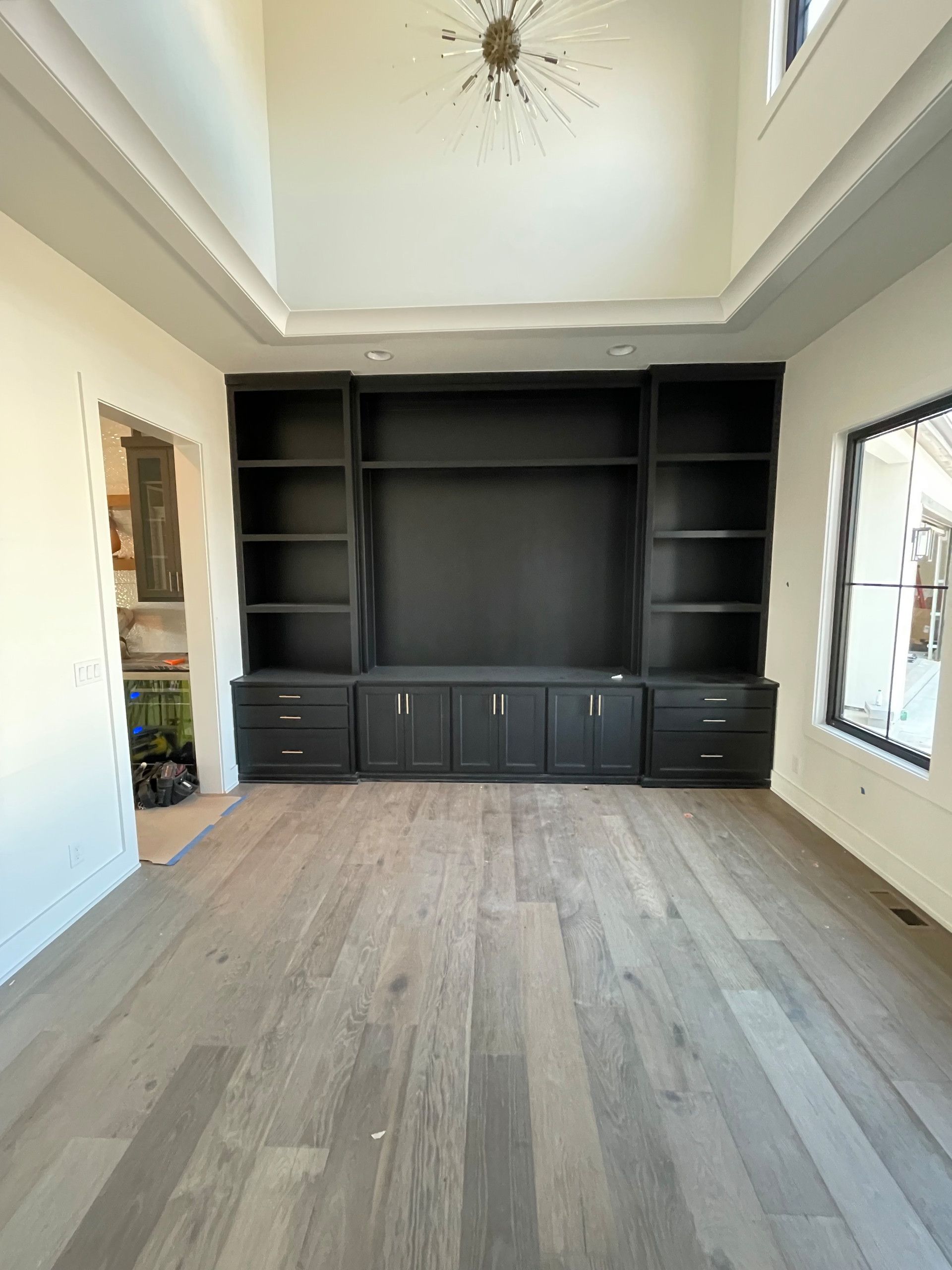 An empty living room with hardwood floors and a large entertainment center.